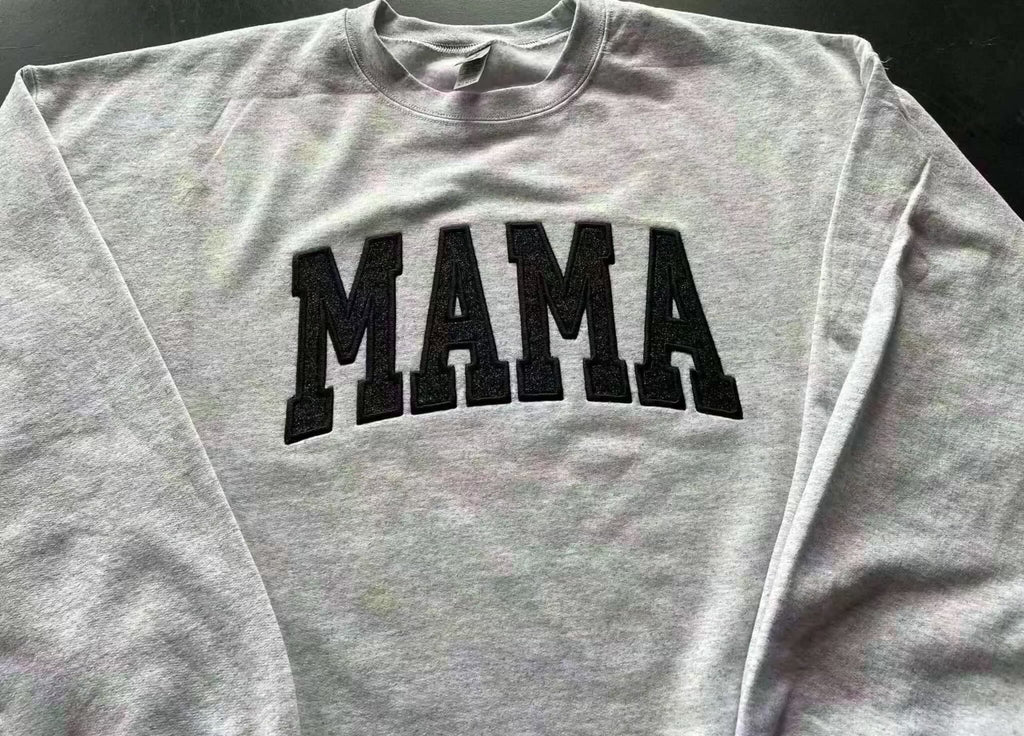 Gray crewneck sweatshirt with embroidered black "MAMA" design in glitter detail