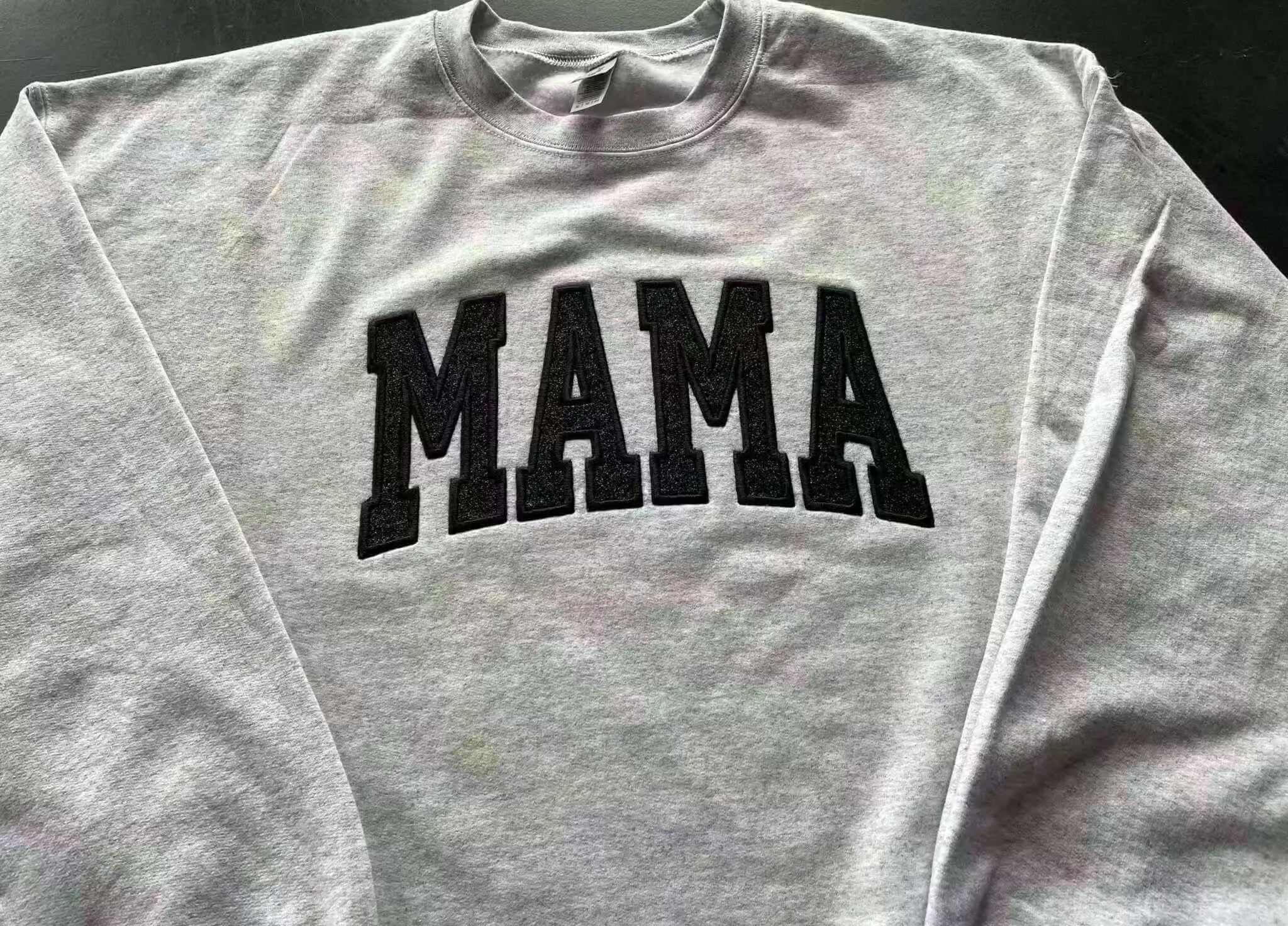 Gray crewneck sweatshirt with embroidered black "MAMA" design in glitter detail