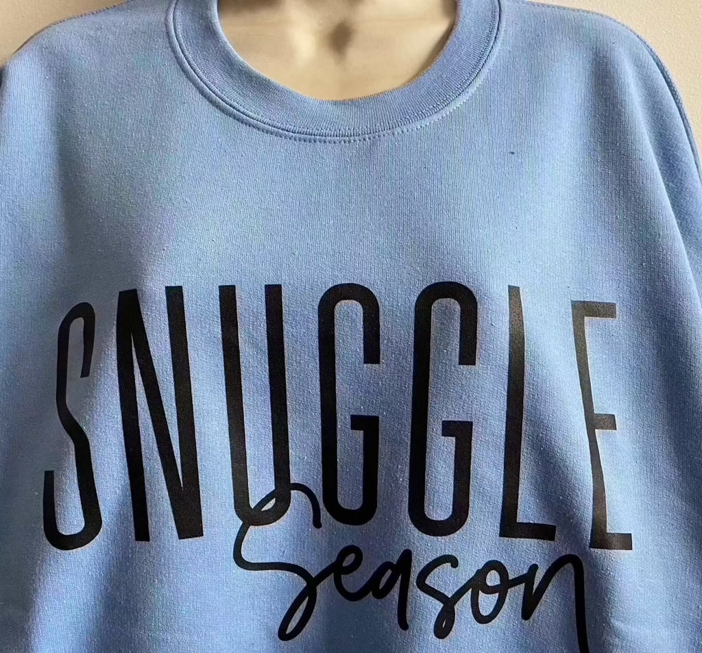 Blue cotton crewneck sweatshirt with "Snuggle Season" text for cozy warmth