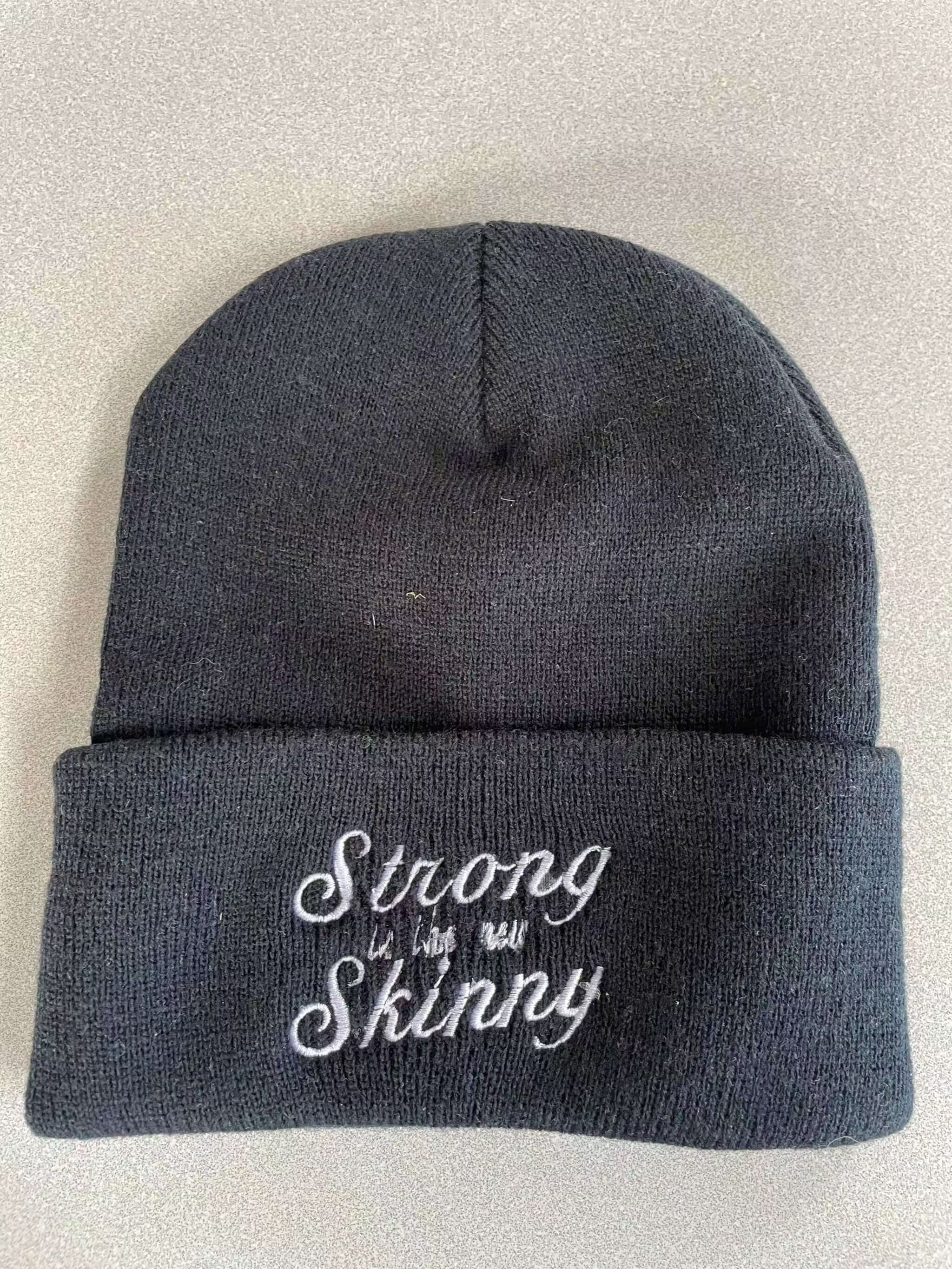 Black warm knit hat with embroidered "Strong Skinny" logo, cuffed design for winter warmth