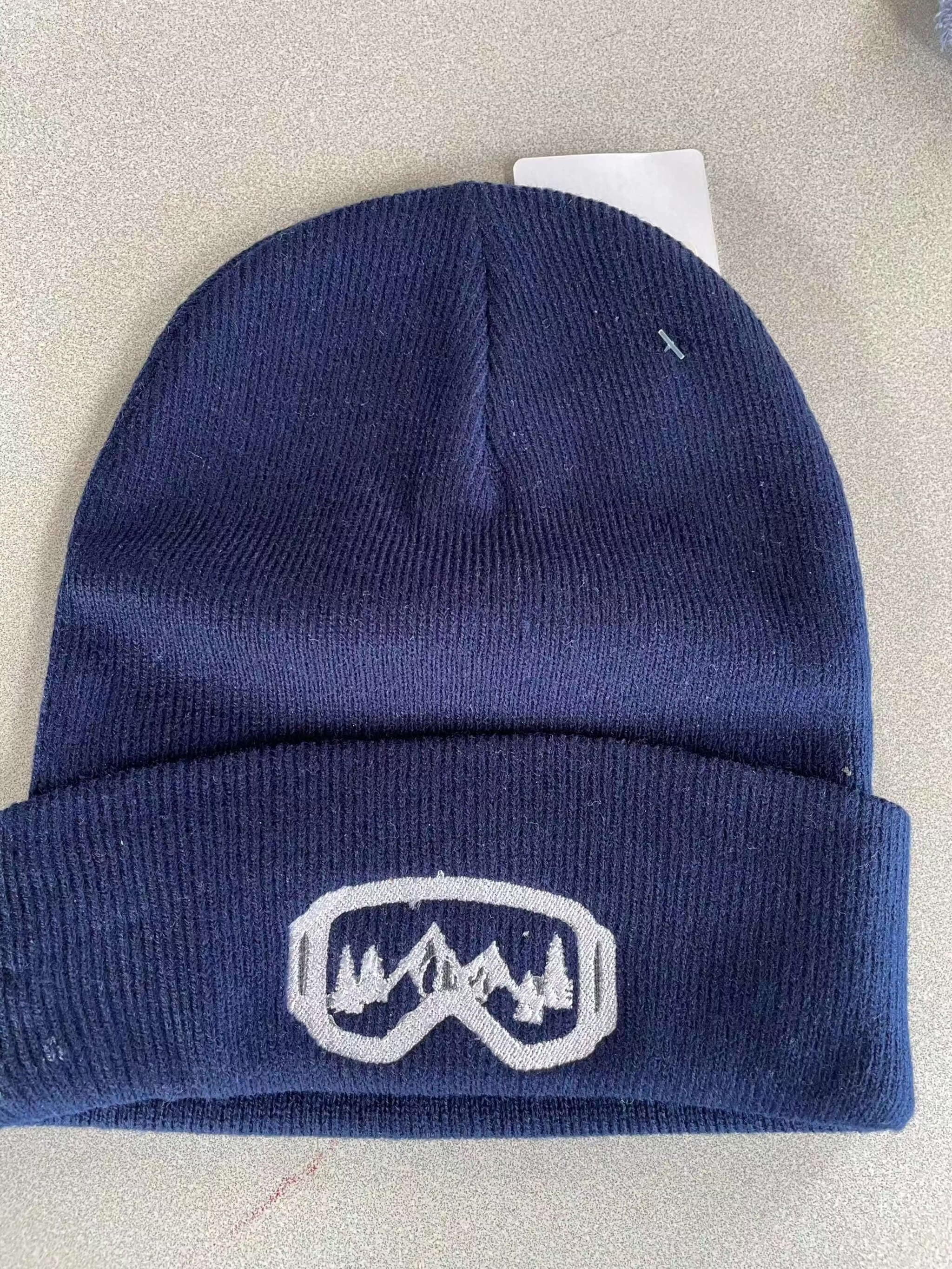 Navy warm knit hat with embroidered mountain and ski goggles logo, cuffed design for winter warmth