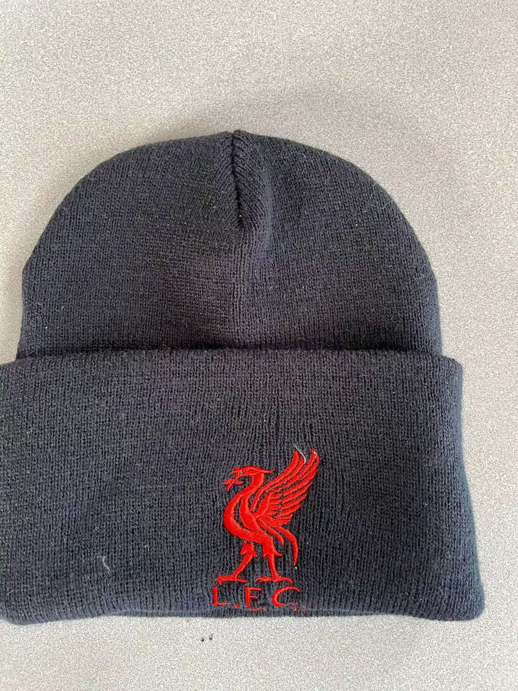 Black warm knit hat with red embroidered logo and cuffed design for winter warmth