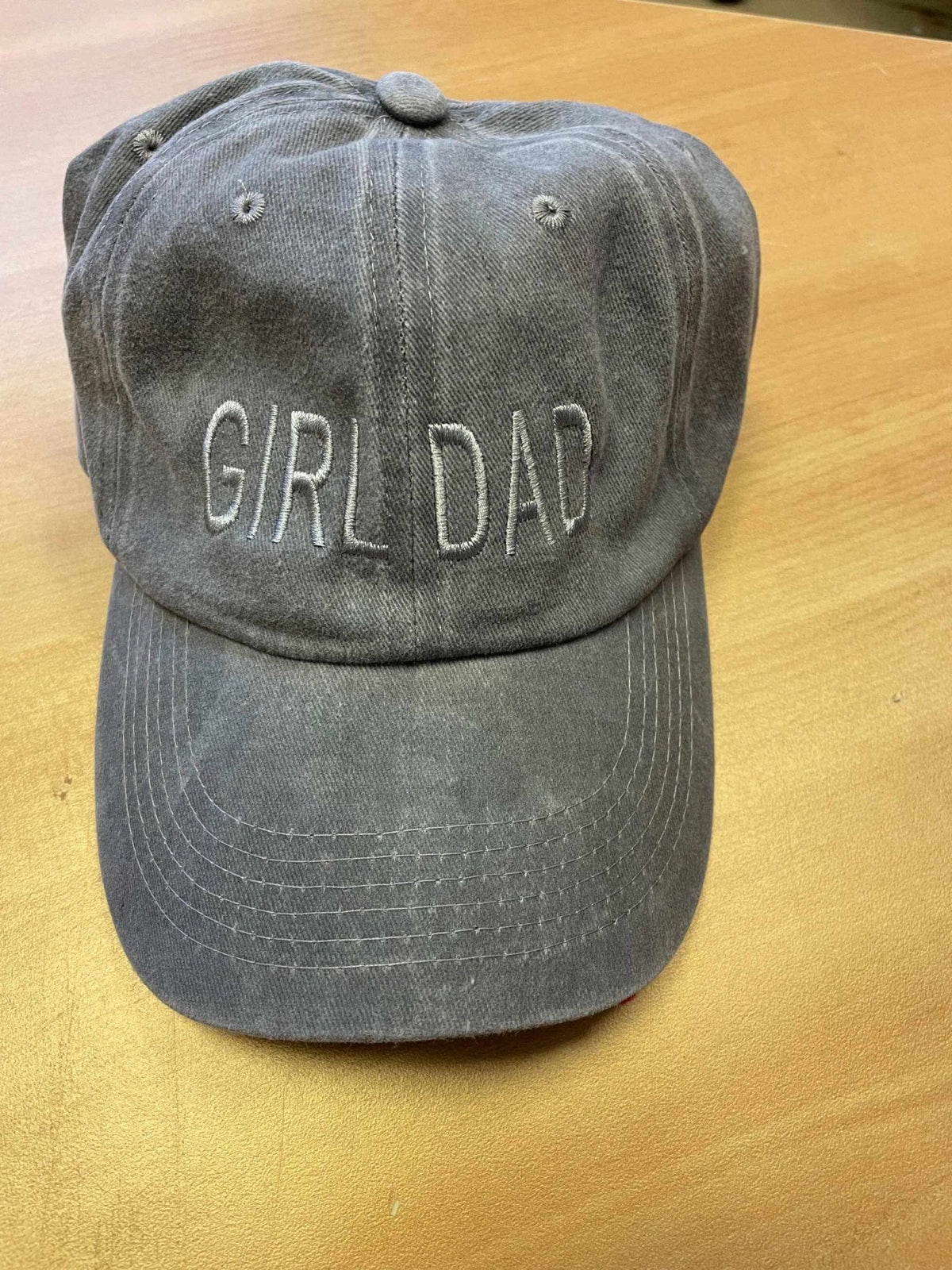 Gray "Girl Dad" baseball hat with adjustable strap on wooden surface