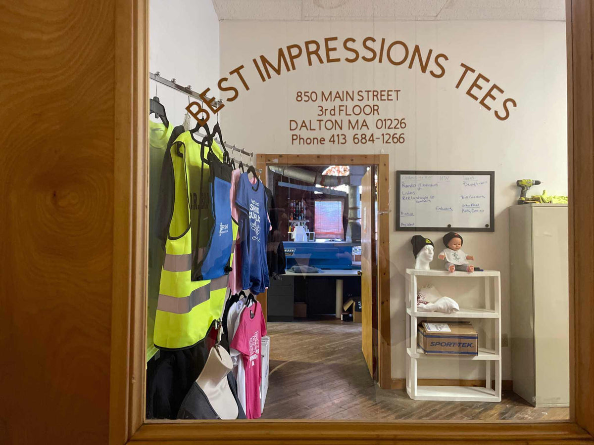 Best Impressions Tees shop window with custom work attire and gift certificate details