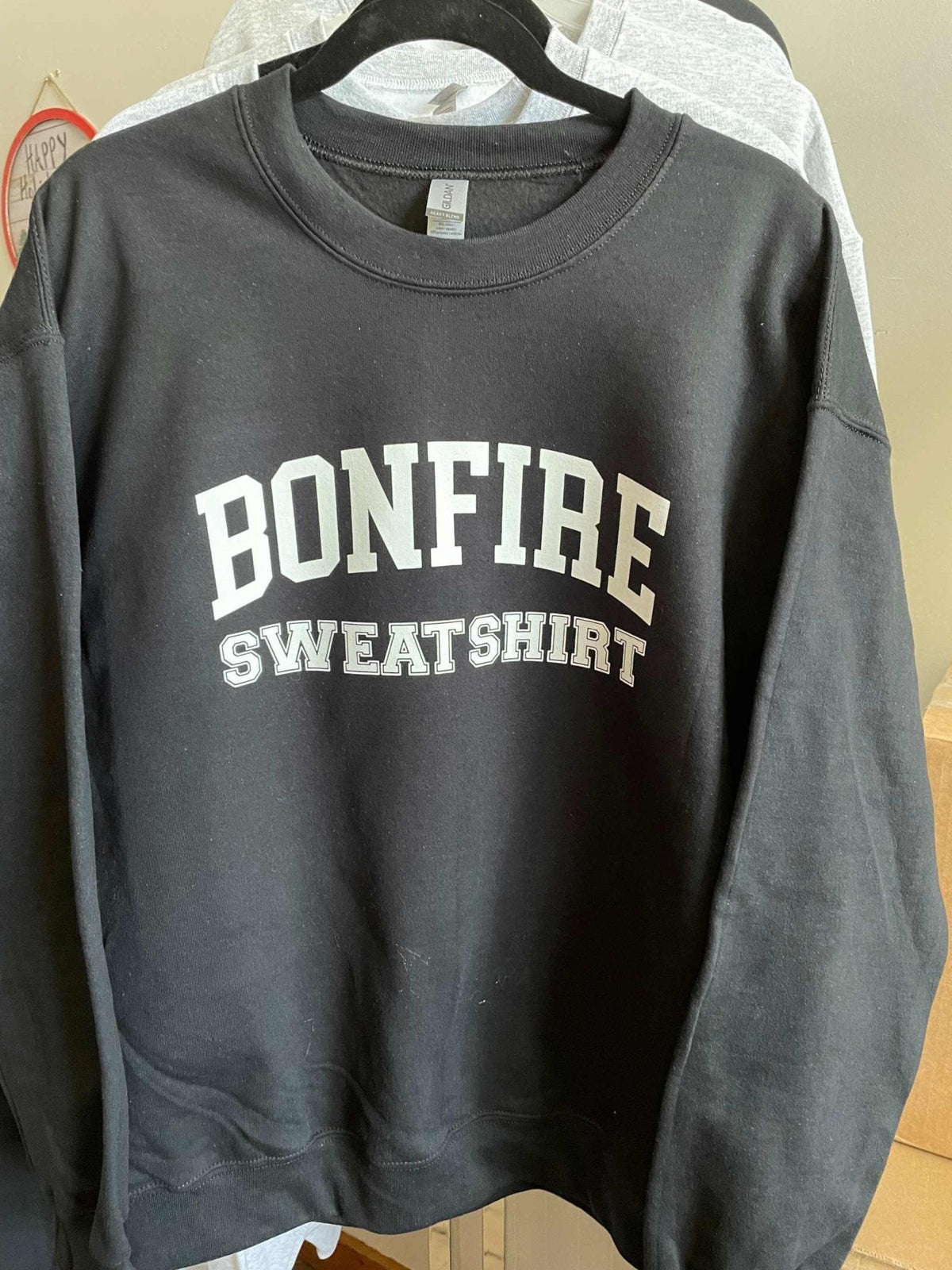 Black Gildan crewneck sweatshirt with white Bonfire Sweatshirt text, cozy cotton blend design