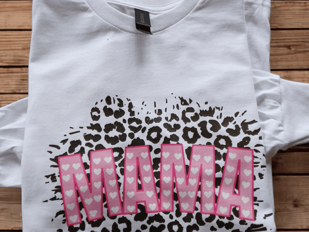 White graphic tee with MAMA text in pink hearts and leopard print background on long sleeve cotton shirt