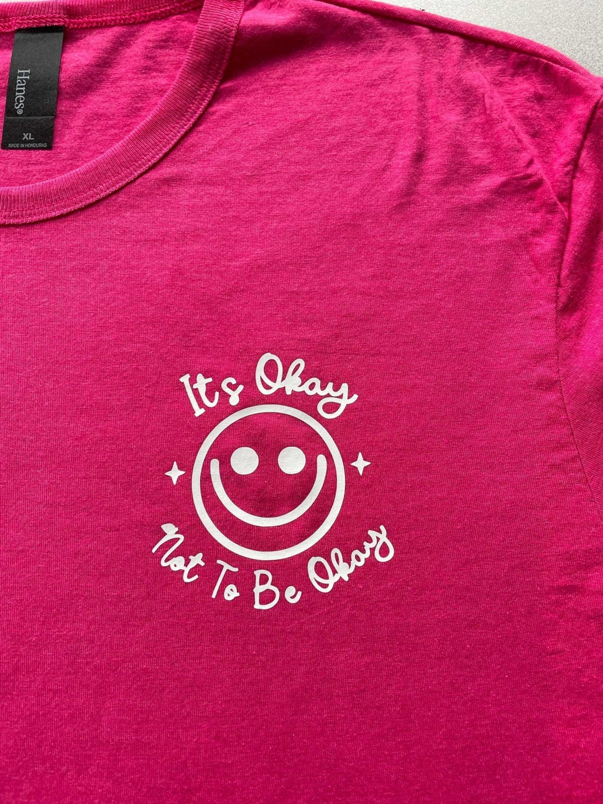 Purple Heather graphic tee with "It's Okay Not to Be Okay" smiley design for women