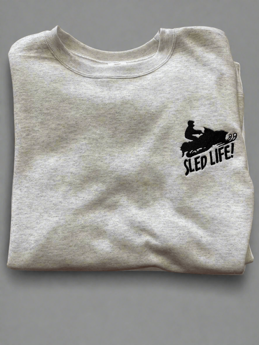 Grey cotton crewneck sweatshirt with embroidered snowmobile sled and "Sled Life" text for winter adventure enthusiasts