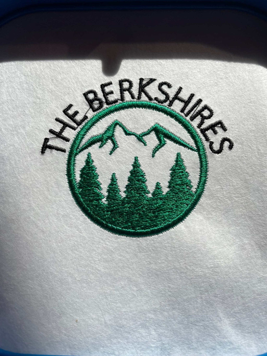 Embroidered logo of The Berkshires with mountain and tree design on soft white Berkshires Sweatshirt